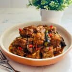 Tender pieces of pork cooked in a savory shrimp paste sauce, served alongside fried eggplant slices.