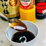 A glossy, savory-sweet sauce with a rich umami flavor, perfect for drizzling over sushi or grilled dishes being poured from a spoon.