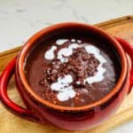 A comforting bowl of chocolate rice porridge (champorado) infused with rich cocoa flavor, complemented by the creamy addition of half and half milk, creating a luscious and indulgent breakfast or dessert.