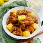 Succulent pineapple chicken served in a bowl alongside fluffy white rice, showcasing tender chicken pieces cooked in a tangy pineapple sauce, perfect for a delicious and satisfying meal.