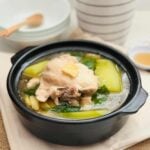 Chicken tinola soup with papaya on a black claypot.