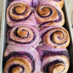 Freshly baked ube rolls on a baking pan.