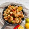 Tofu sisig on black sizzling pan with calamansi an chili on the side.