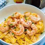 Cajun shrimp on top of fettucine pasta cooked on a creamy cajun white sauce with chopped parsley on top.