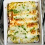A casserole dish filled with cheesy chicken enchiladas, baked to golden perfection.