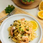 Plate of shrimp and anchovies pasta topped with fried capers, showcasing a savory seafood dish with a crispy garnish.