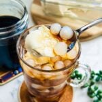 A warm breakfast or snack of Filipino taho, featuring layers of soft tofu, translucent sago pearls, and a sweet brown sugar sauce, all contained in a glass.