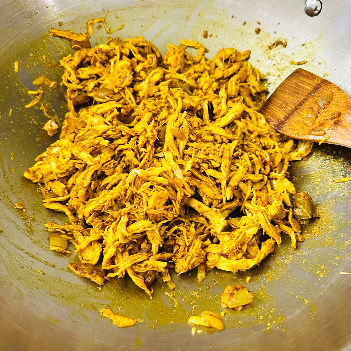 Chicken pastil simmering as sauce reduces and coats the chicken.