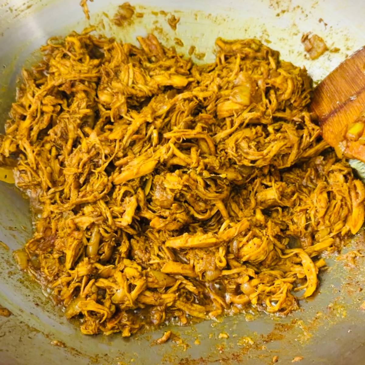 Chicken pastil simmering as sauce reduces and coats the chicken.
