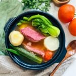 Sinigang na corned beef: a savory and tangy Filipino stew featuring tender corned beef chunks simmered in a flavorful sour broth with vegetables bokchoy, gabi, okr, daikon raddish and green chili, served hot in a bowl.