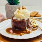 Sticky toffee pudding inspired by Gordon Ramsay's Hell's Kitchen: a decadent dessert consisting of moist sponge cake infused with dates, covered in a rich toffee sauce, served warm with a dollop of vanilla ice cream.