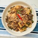 A dish of Cereal Butter Tofu, featuring crispy tofu cubes coated in a golden, buttery sauce with crunchy cereal pieces scattered on top.