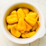 A serving plate filled with glistening sweetened jackfruit slices, showcasing their vibrant yellow color and juicy texture.