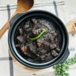 Tinumis served in a traditional black clay pot, showcasing a savory Filipino stew.