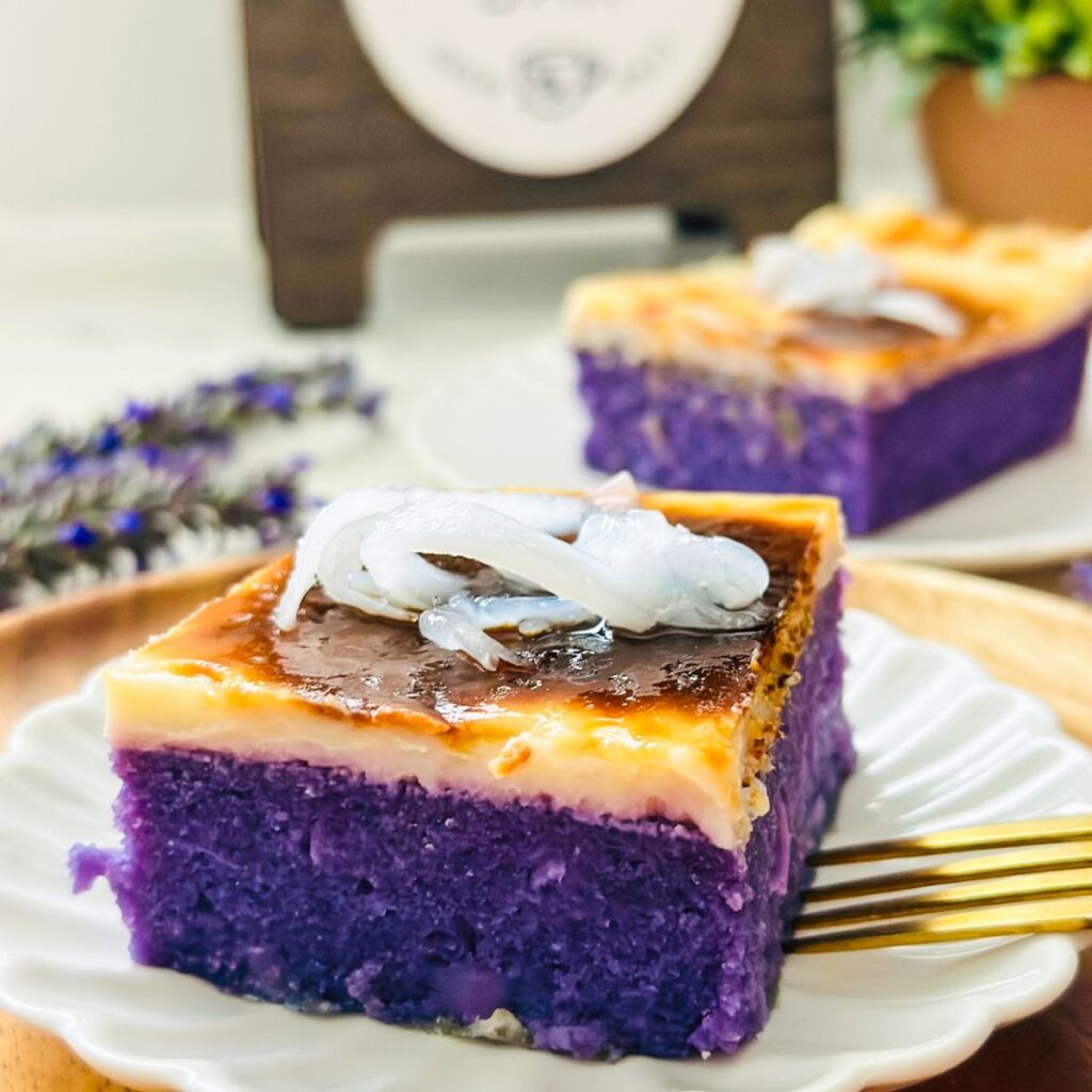 Ube cassava cake topped with macapuno (coconut sport) on a serving plate, showcasing a delightful purple and white contrast.