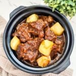 Beef Adobo in a claypot, featuring tender beef pieces simmered in a rich, savory sauce, with golden-brown fried potatoes mixed in.