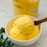 Smooth and creamy Ninja Creami Mango Ice Cream in a bowl, showcasing a rich, vibrant yellow color.