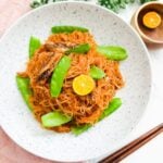 A plate of pancit bihon, a Filipino noodle dish, topped with canned sardines.