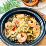 Overhead view of a clay pot filled with the Best Laing Recipe with Shrimp (Taro Leaves in Coconut Milk).