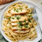 A plate of fettuccine pasta tossed in a creamy Alfredo sauce, topped with tender chicken.