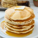 Close-up of McDonald's Copycat Pancakes stacked on a plate. The fluffy, golden-brown pancakes are drizzled with syrup and topped with a pat of butter, replicating the classic look and texture of McDonald's famous pancakes.
