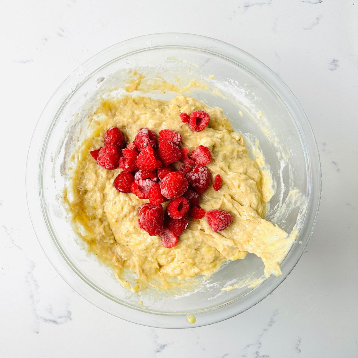 Adding frozen raspberries into the banana batter.