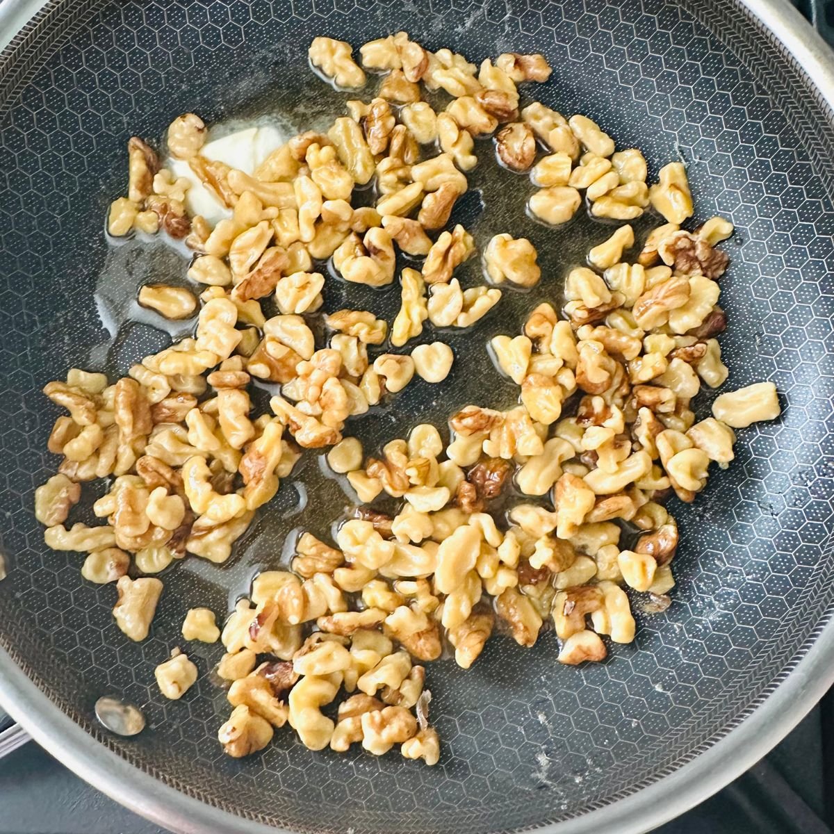Butter melting in a nonstick skillet to start candied maple walnut recipe.