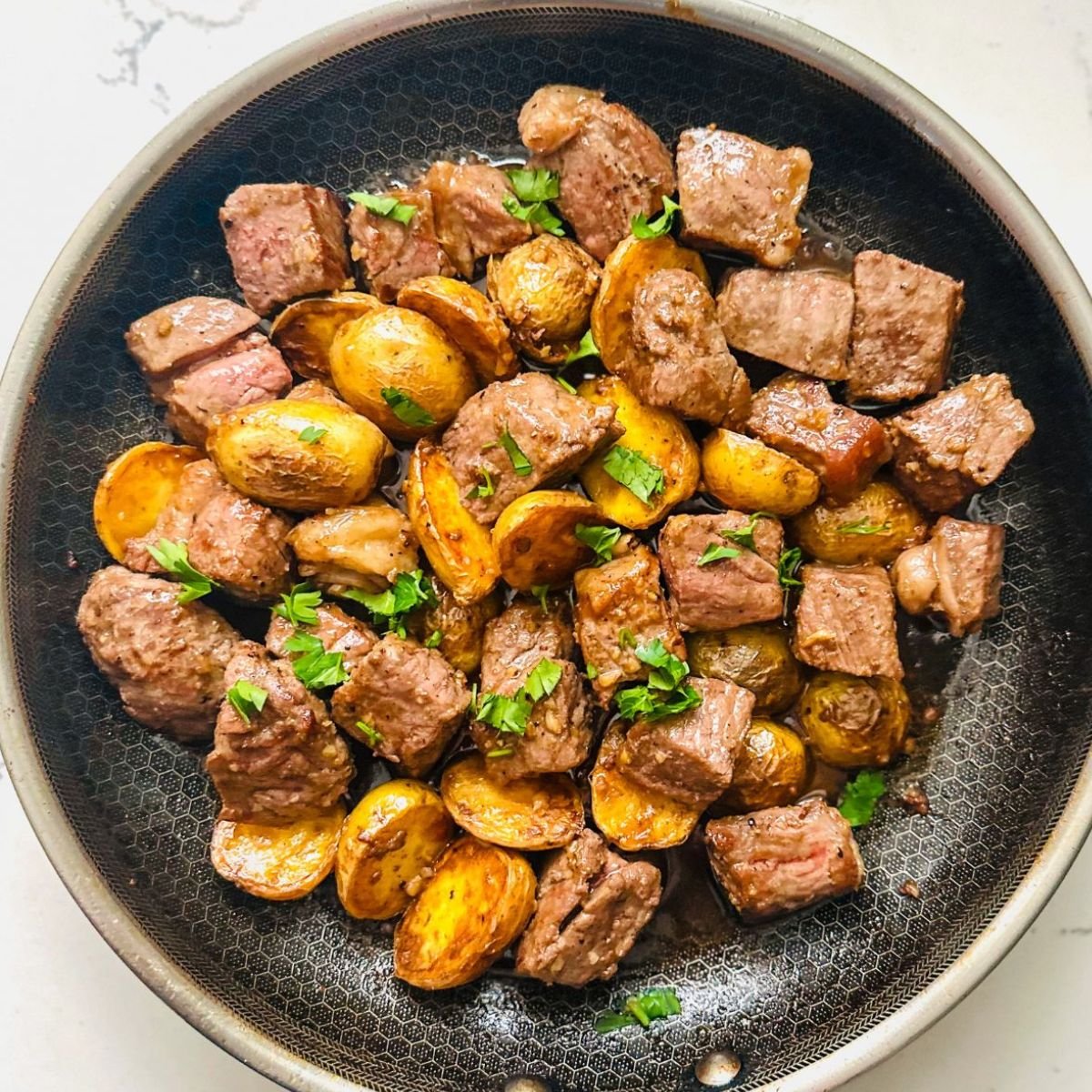 Garlic Butter Steak Bites sizzling in skillet with herbs and potatoes โ easy 20-minute beef dinner idea.
