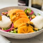 A cozy fall salad featuring spring mix, burrata, and ripe persimmon — a bright, creamy, and fresh seasonal dish.