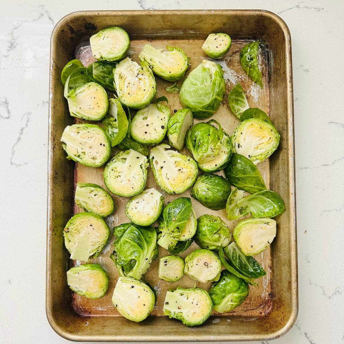 Brussels sprouts with salt and pepper on a baking pan.