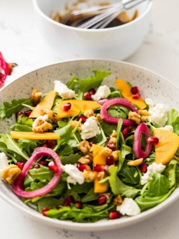 Easy arugula and pomegranate salad with goat cheese, candied walnuts, and balsamic dressing — simple fall salad recipe.