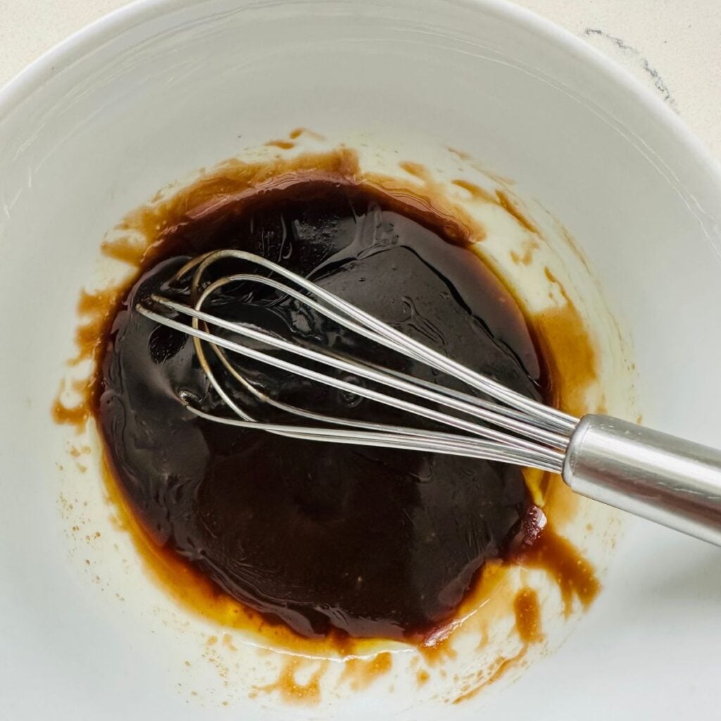 Homemade balsamic vinaigrette in a small bowl with olive oil, maple syrup, salt, and black pepper — easy salad dressing recipe.