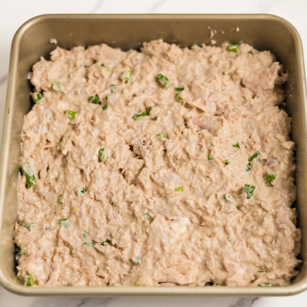 Seasoned rice topped with tuna mixture ready for baking.