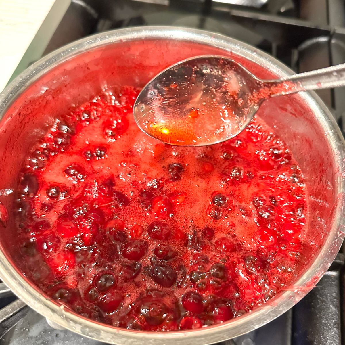 Simmering sugar free cranberry sauce without added sugar, thick and glossy.