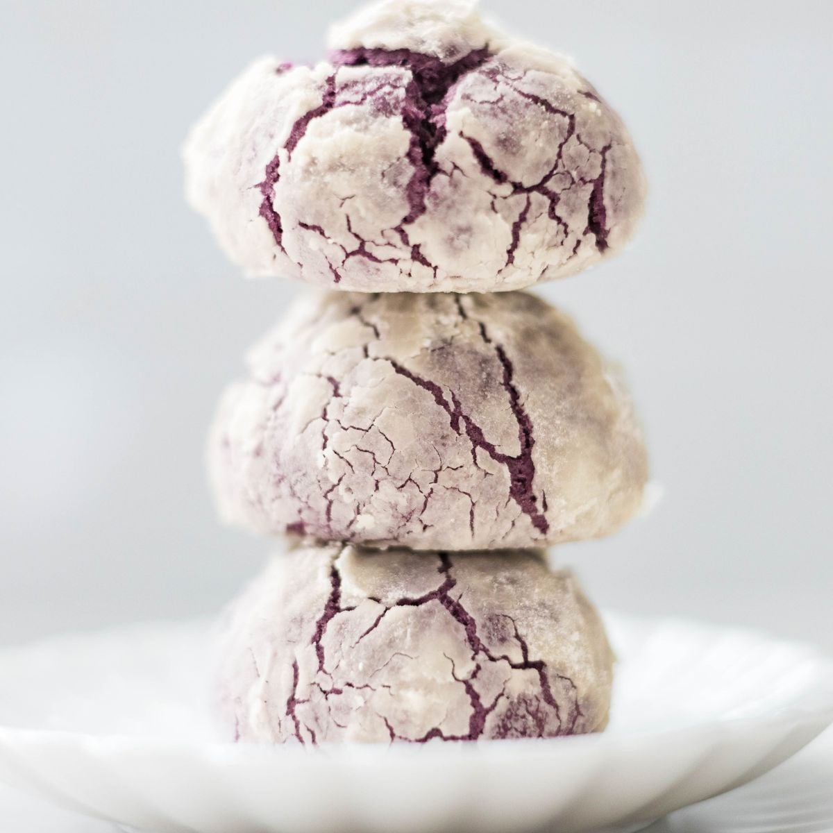 Stack of ube crinkle cookies with cracked sugar tops and fudgy purple interior.