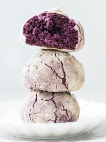 Freshly baked ube crinkle cookies stacked, showing soft moist purple center and crackled tops.