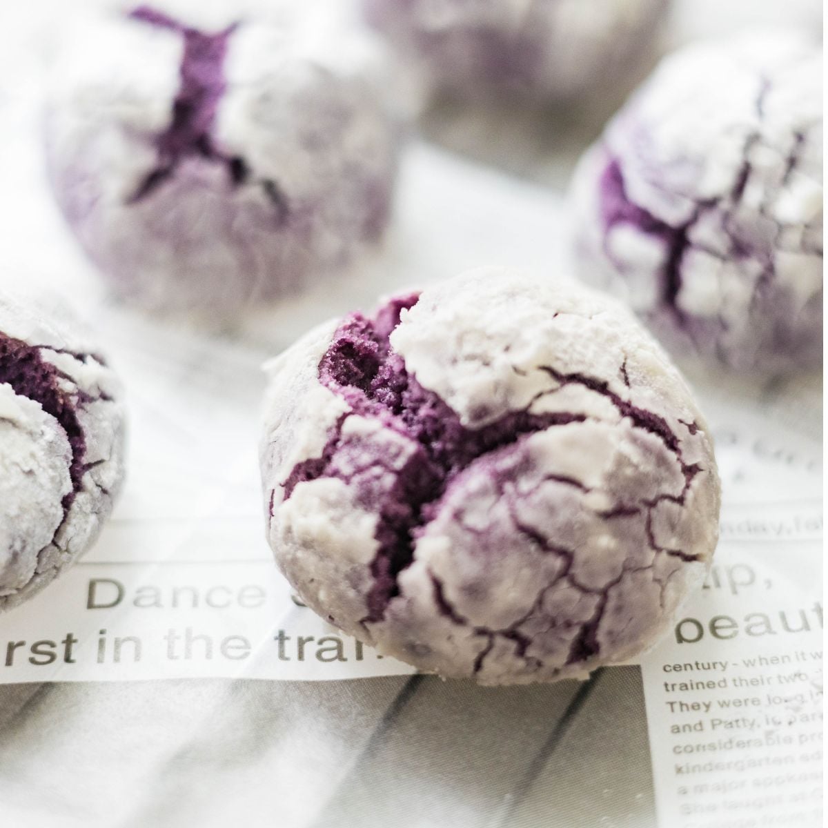 Freshly baked ube crinkle cookies cooling on a wire rack with crisp, cracked tops