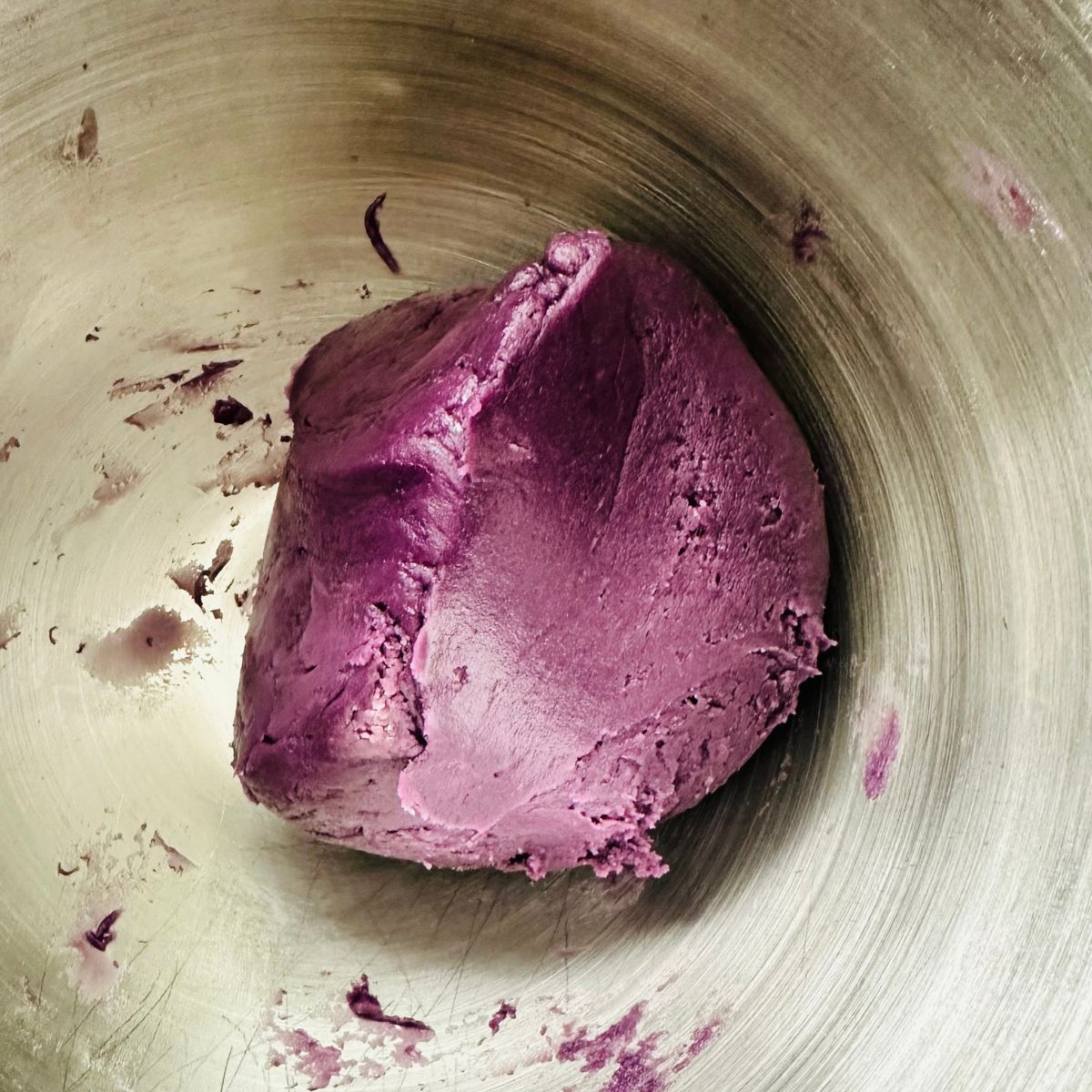 Purple ube cookie dough resting in a stainless bowl before baking.