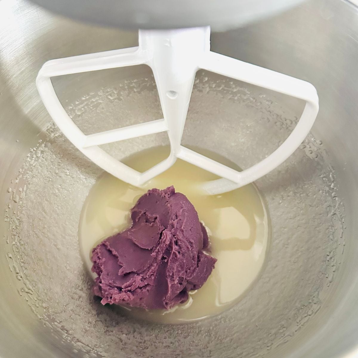 Mixing sugar, oil, egg, ube halaya in a bowl for ube crinkle cookie dough.