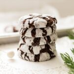 Pile of homemade chocolate crinkle cookies with crackled powdered sugar tops.