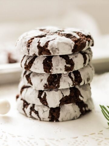 Pile of homemade chocolate crinkle cookies with crackled powdered sugar tops.