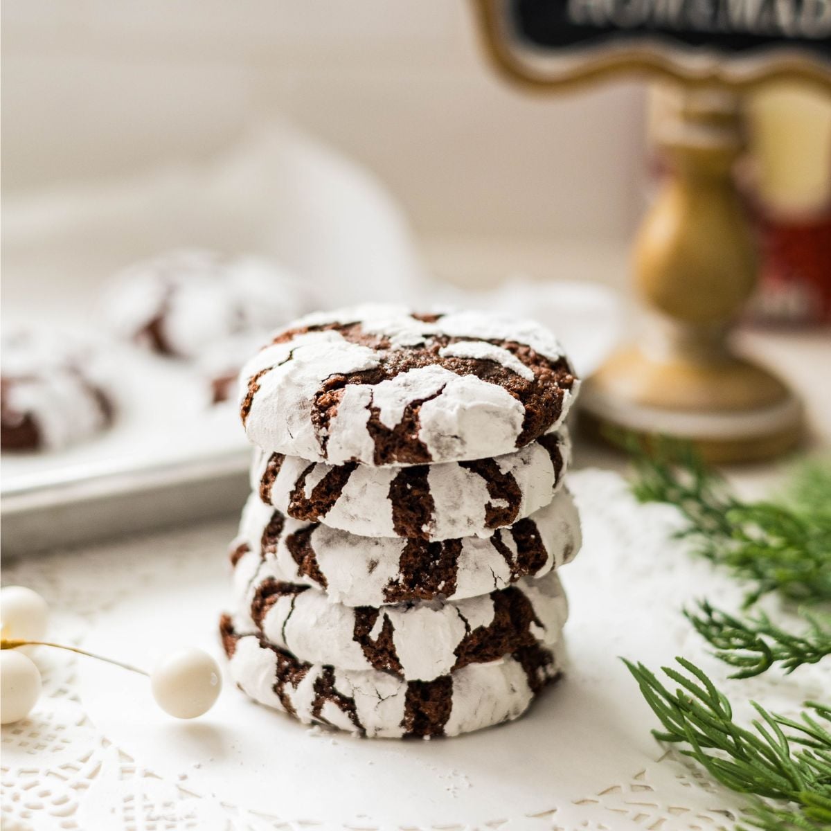 Stacks of fudgy chocolate crinkles coated in powdered sugar on a plate.