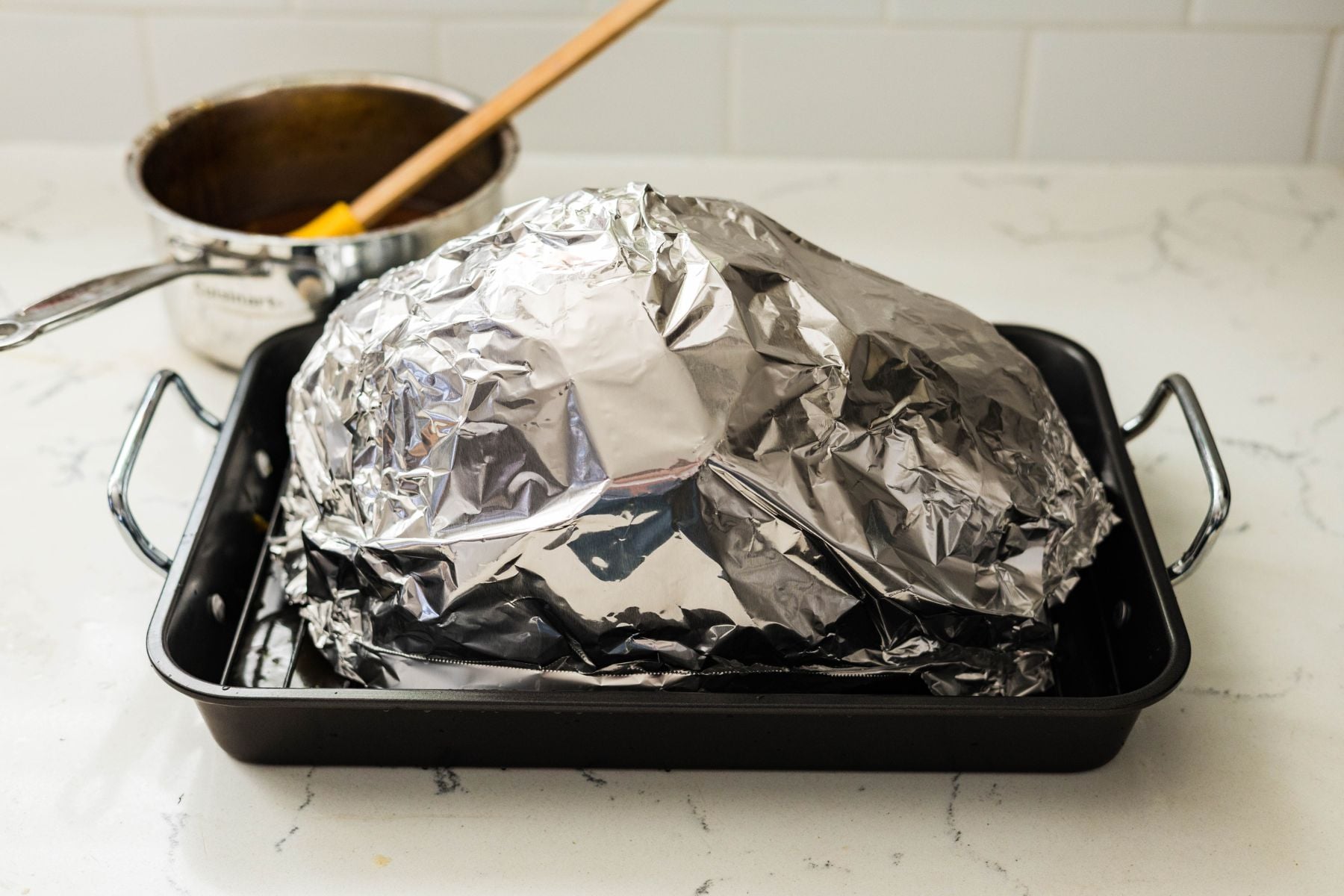 Orange maple glazed spiral ham covered with alumunim foil ready for baking.