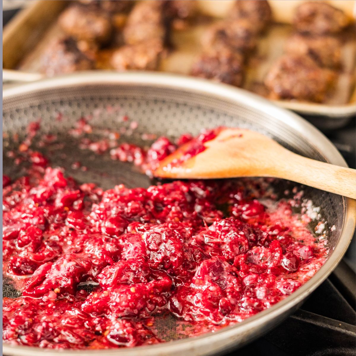 Homemade cranberry sauce simmering in a skillet pan.