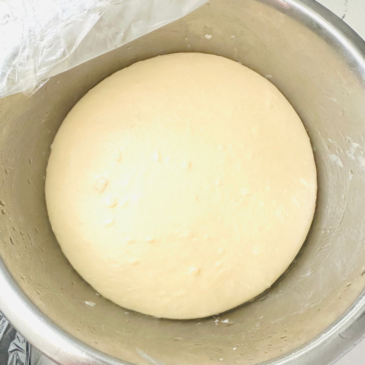 reshly mixed pandesal dough resting in a metal mixing bowl before the first rise.