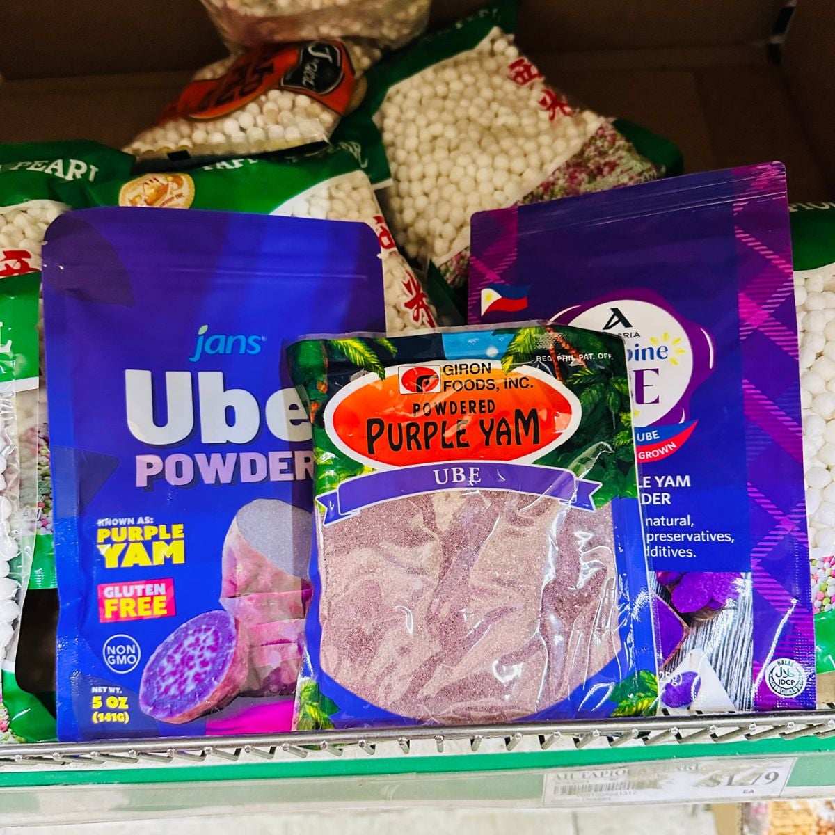 Different brands of ube powder or powdered purple yam on a store shelf.