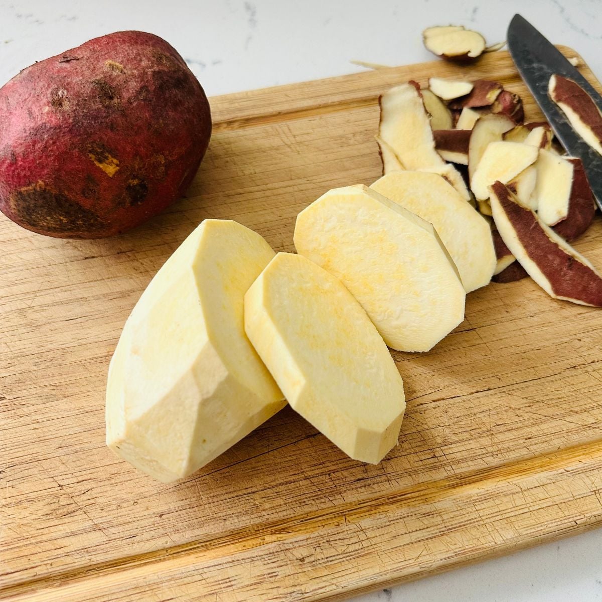 Camote cue recipe sliced sweet potatoes on cutting board before frying.