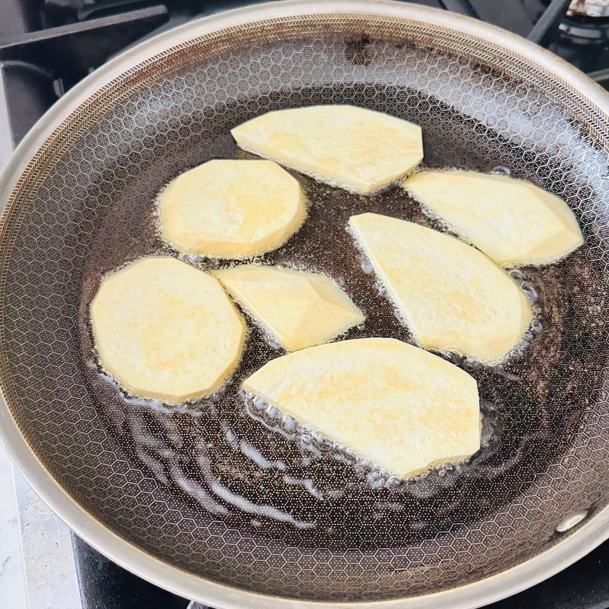 Camote cue recipe frying sliced sweet potatoes in oil in pan.