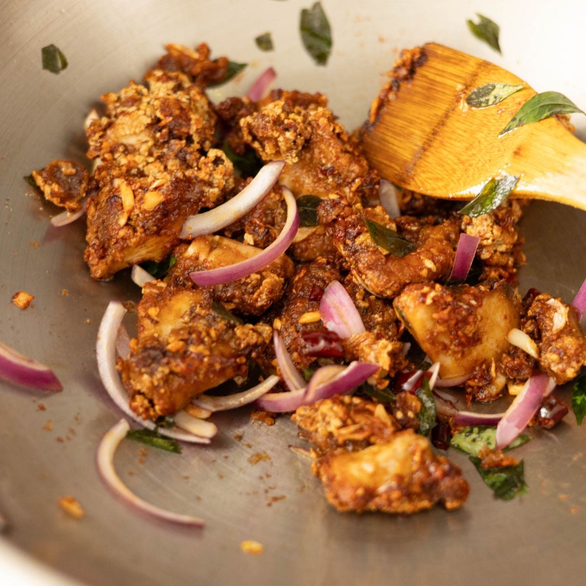 Crispy Chicken 65 plated with red onions and curry leaves