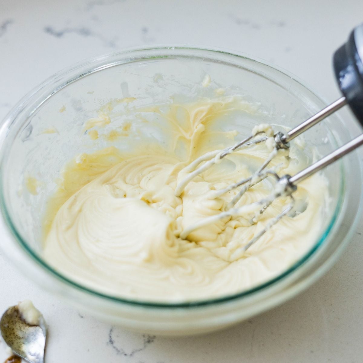 Creamy cinnamon roll cream cheese frosting being blended until smooth and fluffy